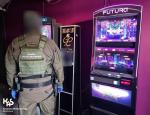 funkcjonariusz Służby Celno-Skarbowej stoi tyłem przy nielegalnym automacie do gry