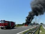 płonący samochód na autostradzie, ogień i kłęby dymu, obok wóz gaśniczy Straży Pożarnej